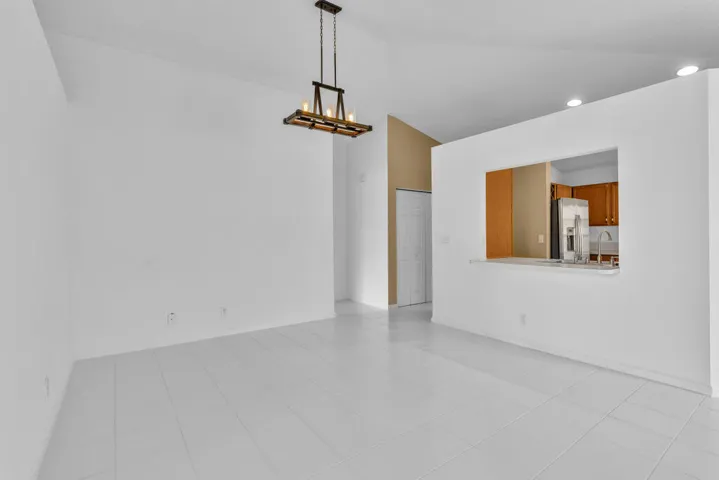 Vaulted ceilings, tile flooring, multi-blade ceiling fan, and linear pendant lighting fixture
