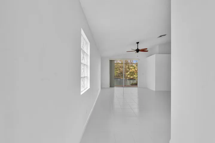 Interior space featuring vaulted ceilings, tile flooring, a glass block window, and a ceiling fan