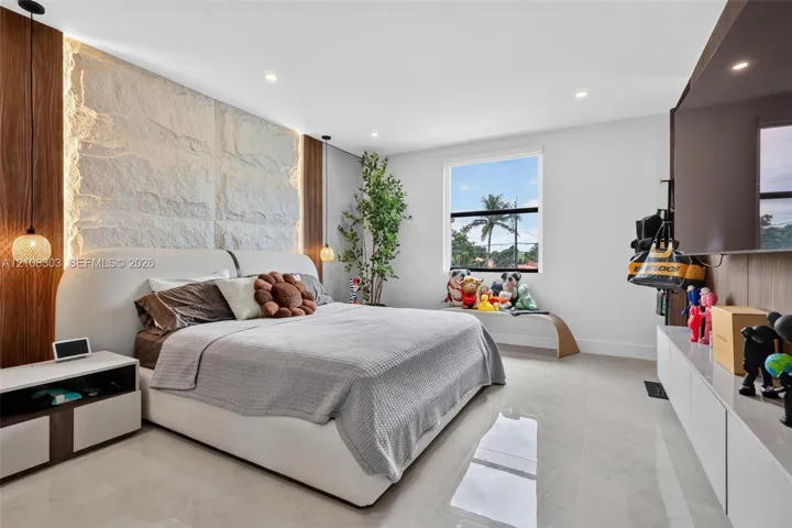 Textured stone feature wall with integrated accent lighting, recessed ceiling lighting, large-format tile flooring, and custom wall-mounted cabinetry