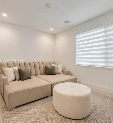 Neutral-toned room featuring recessed ceiling lighting and adjustable window blinds