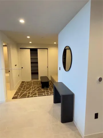Built-in closet with sliding doors and integrated shelving, recessed lighting, and neutral stone-finish flooring