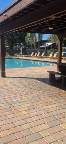 Outdoor living area featuring a wood-beam pergola, paver patio, in-ground swimming pool, and privacy fencing