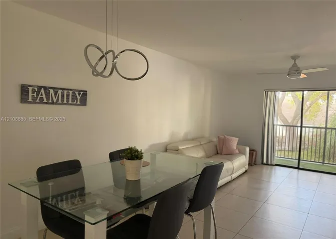Ceramic tile flooring, multi-ring polished chrome pendant light, and sliding glass door leading to a balcony with metal railing