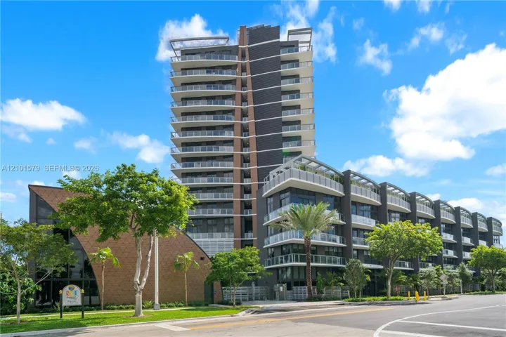 Contemporary high-rise architecture featuring glass-railed private balconies, a multi-story facade with dark paneling, and an attached low-rise structure with textured shingle-style exterior cladding