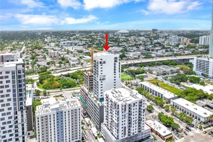 Aerial perspective of a high-rise residential structure featuring a white facade, recessed balconies, and a multi-level architectural design