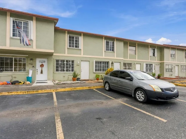 Stucco exterior facade featuring contrasting trim, grid-patterned windows, and dedicated off-street parking