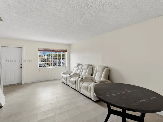 Neutral-toned wall finishes, large-format tile flooring, textured ceiling, and a single-panel entry door