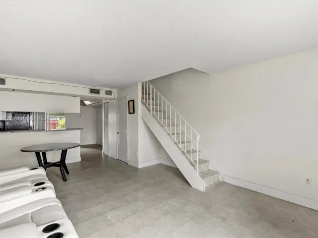 Open-concept interior featuring tile flooring, a built-in kitchen breakfast bar, and a staircase with a metal handrail