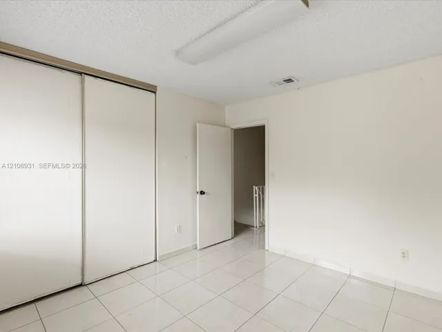 Room featuring ceramic tile flooring, neutral walls, and a large reach-in closet with sliding doors