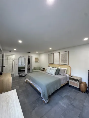 Large-format tile flooring, recessed ceiling lighting, and a built-in arched doorway featuring a mirror