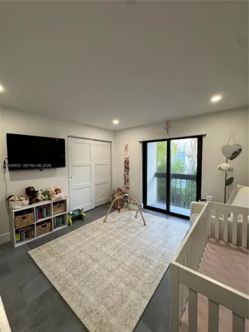 Interior room featuring dark tile flooring, sliding glass door with a black frame, and two-panel closet doors
