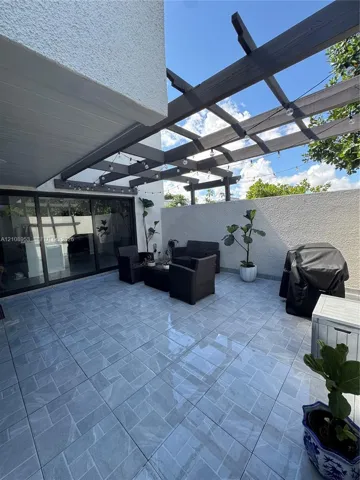 Outdoor patio featuring large-format ceramic tiling, a custom wood-beam pergola, and expansive sliding glass doors