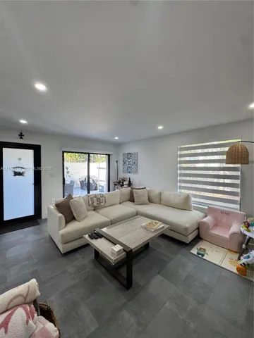 Large-format gray tile flooring, recessed ceiling lighting, sliding glass door, and dual-pane window with horizontal light-filtering shades