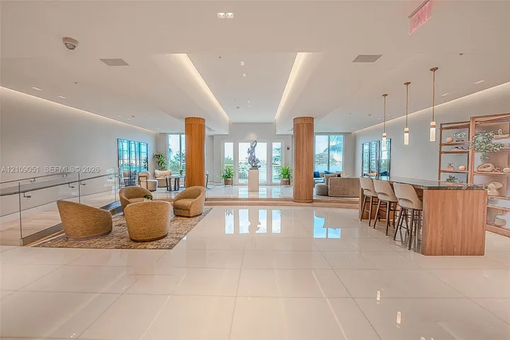Open-concept interior featuring polished tile flooring, wood-clad structural columns, integrated cove lighting, and a built-in bar with matching cabinetry
