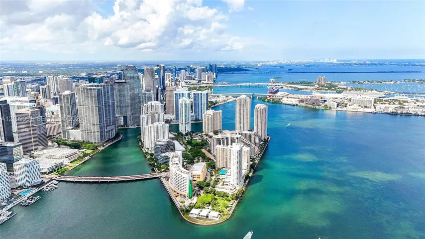 Aerial perspective of a high-density urban peninsula featuring deep-water access, multi-story glass-facade residential towers, waterfront exposure, and proximity to a metropolitan skyline