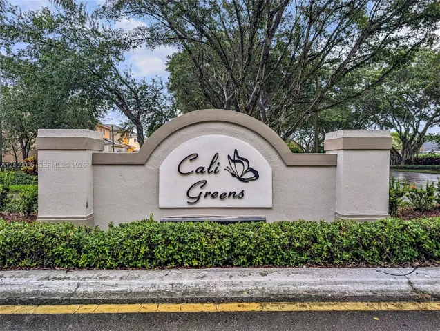 Cali Greens community signage featuring a stucco monument with tiered concrete caps and mature perimeter landscaping