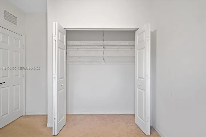 Reach-in closet featuring white bifold doors and integrated wire shelving