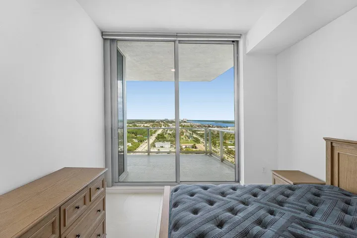 Floor-to-ceiling glass sliding doors opening to an expansive private balcony featuring a glass railing and elevated horizon exposure