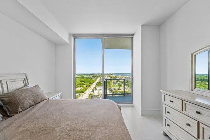 Floor-to-ceiling glass sliding door, balcony access, and light-toned tile flooring