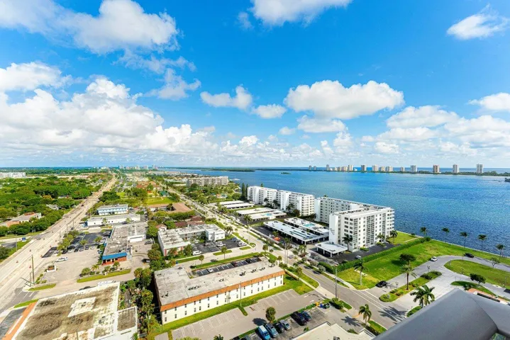 Aerial perspective of the coastline, featuring expansive water frontage, mature palm trees, and multi-story structural architecture