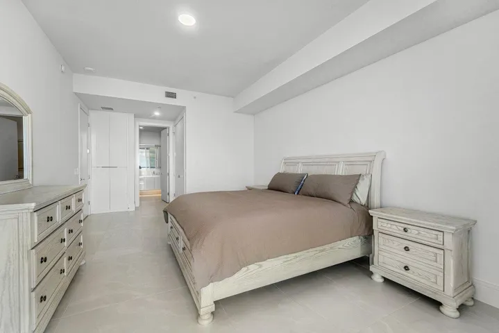 Interior space featuring neutral stone-finish tile flooring, recessed ceiling lighting, and floor-to-ceiling built-in cabinetry