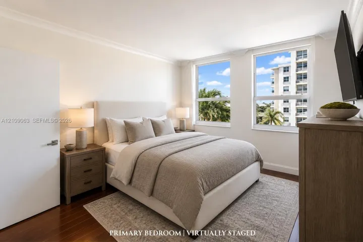 Room featuring wood-finish flooring, dual windows, and crown molding