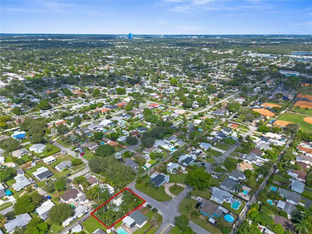 Aerial perspective of a corner lot property featuring established mature trees and perimeter greenery