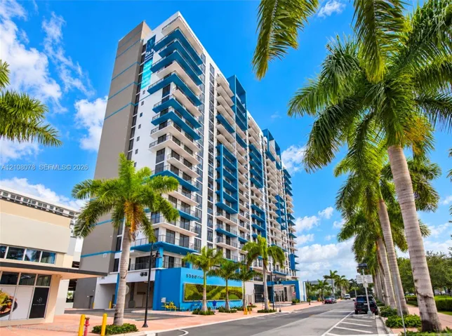 High-rise exterior featuring a multi-story glass facade, blue structural accents, private balconies, and an exterior living plant wall