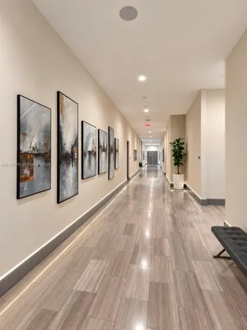 Wide hallway featuring neutral wall finishes, stone-textured flooring, integrated wall-level LED accent lighting, and recessed ceiling lighting