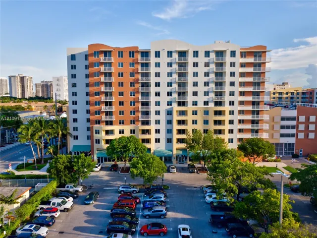 Multi-story residential building featuring a stucco exterior, private balconies, and dedicated surface parking