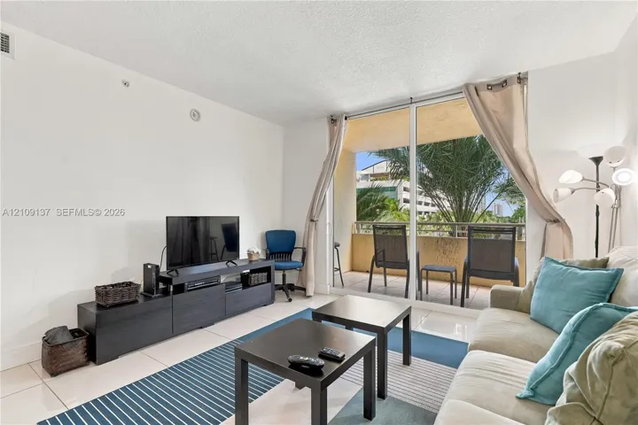 Living area featuring large-format tile flooring and floor-to-ceiling glass sliding doors providing access to a private balcony