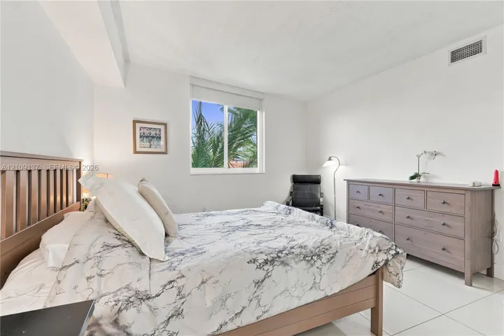Spacious room featuring neutral wall tones, large-format tile flooring, and a single-pane sliding window