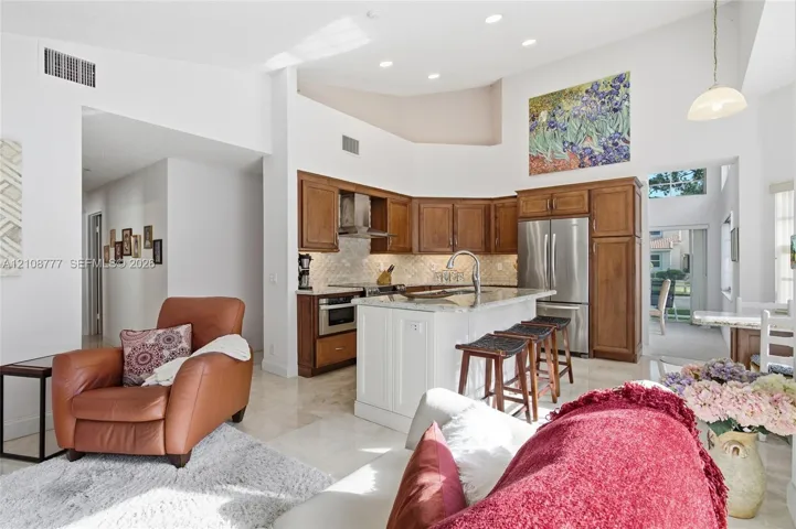 Kitchen featuring vaulted ceilings, recessed lighting, stone-surface center island with seating, and wood-finish cabinetry