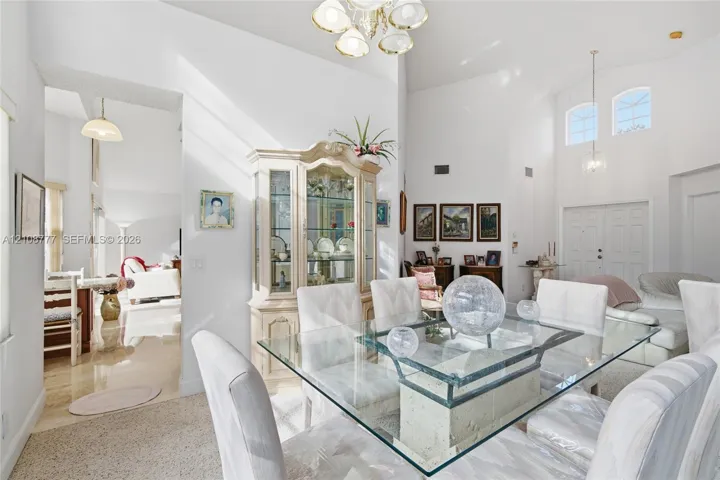 Dining area featuring vaulted ceilings, arched windows, multi-tiered chandelier, and recessed lighting