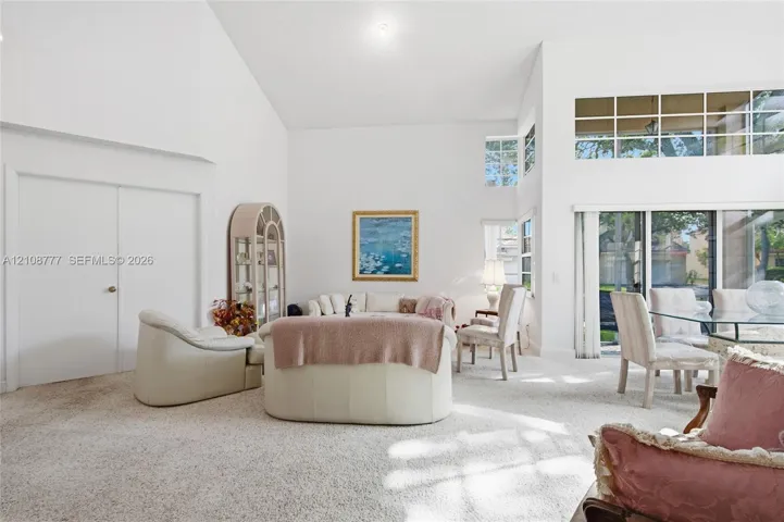 High vaulted ceilings featuring clerestory windows, sliding glass doors, and a neutral color palette