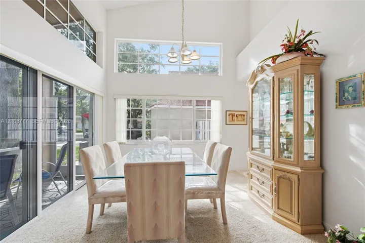 Dining area featuring vaulted ceilings, clerestory windows, multi-pane picture windows, sliding glass doors, and a decorative pendant light fixture
