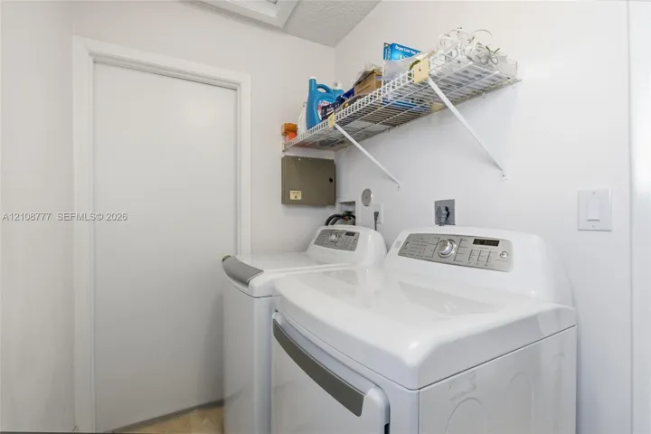 Laundry area featuring white appliance hookups and a mounted wire shelving unit