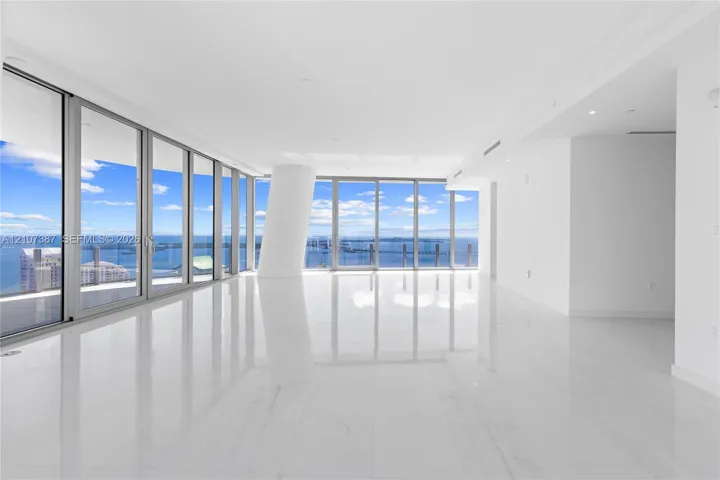 Floor-to-ceiling windows featuring panoramic water scenery, polished stone-finish flooring, and a structural column