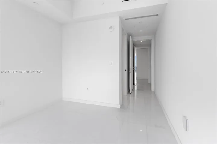 Neutral interior featuring high-gloss tile flooring, recessed ceiling lighting, and smooth-finish walls