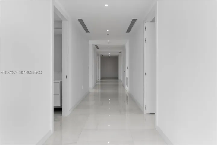 Hallway featuring polished tile flooring, recessed ceiling lighting, and integrated linear fixtures