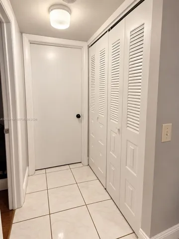 Tiled flooring, dual louvered-panel closet doors, and a ceiling-mounted light fixture