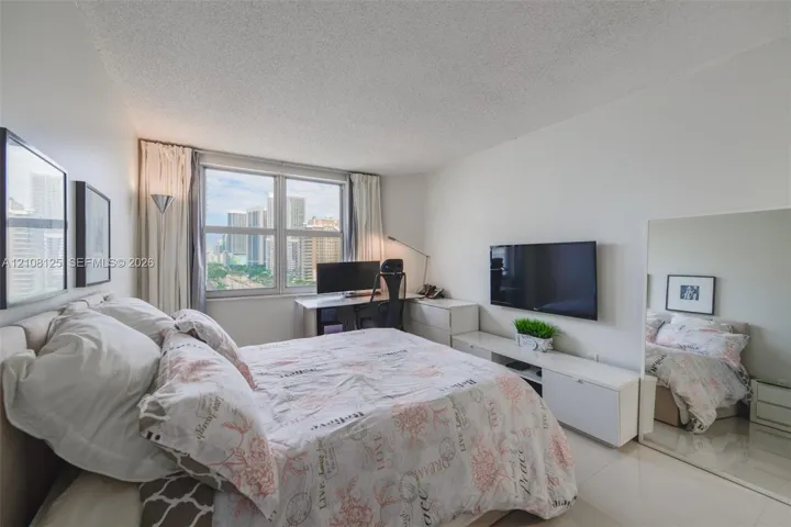 Bright room featuring large-format tile flooring, textured ceiling, expansive window, and integrated mirrored wall panel