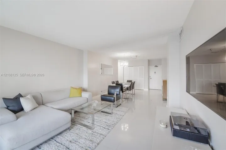 Open-concept interior featuring light-toned tile flooring, neutral wall paint, a multi-light chandelier, and full-height bi-fold closet doors