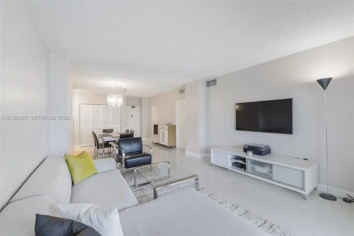 Open-concept living space featuring high-gloss tile flooring, neutral wall tones, and a crystal chandelier