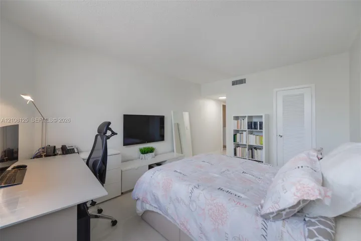 Neutral interior room featuring white walls, tile flooring, and a single-panel door with a louvered detail