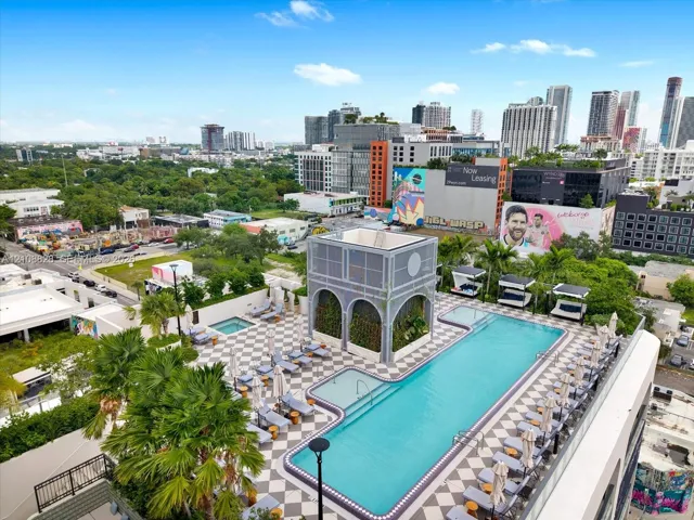 Rooftop amenity deck featuring a large swimming pool, integrated spa, checkered tiling, decorative architectural structure, and landscaping