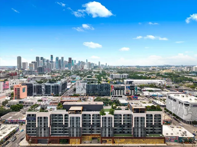 Multi-story residential complex featuring white architectural arches, dark metal paneling, integrated rooftop greenery, and private balconies