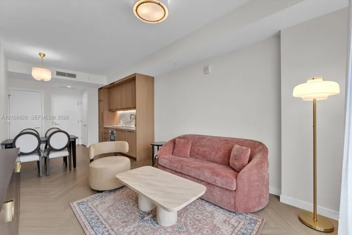 Open-concept living space featuring wood-finish herringbone flooring, custom light wood cabinetry, stone backsplash, and recessed ceiling lighting