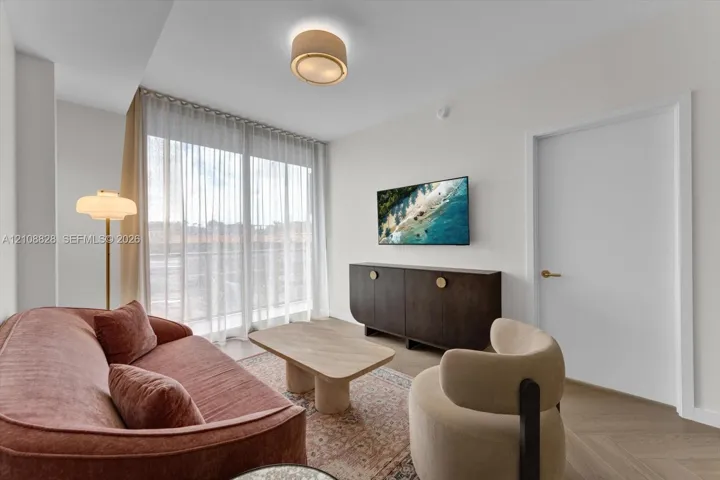 Floor-to-ceiling glass sliding doors, wood-finish flooring in a herringbone pattern, drum-style flush mount ceiling light, and clean-lined interior finishes