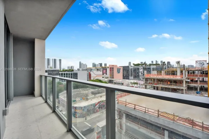 Covered balcony featuring concrete flooring and a glass panel railing